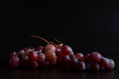 Red grapes, large bunch of fruits, fresh and tasty simple food on a dark background in a fancy minimal composition