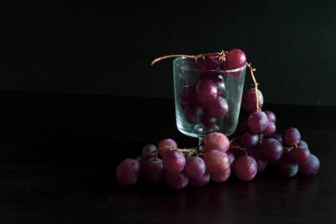 Red grapes, large bunch of fruits, fresh and tasty simple food on a dark background in a fancy minimal composition