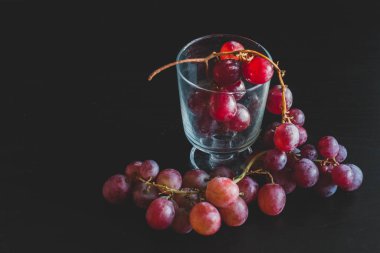 Red grapes, large bunch of fruits, fresh and tasty simple food on a dark background in a fancy minimal composition