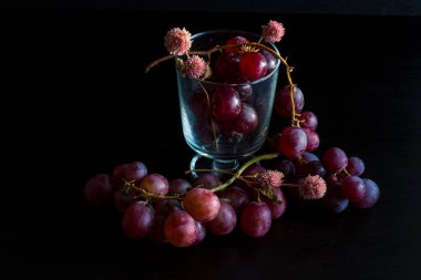 Red grapes, large bunch of fruits, fresh and tasty simple food with bright colors on a black background. flowers and fruit for an artistic food composition.