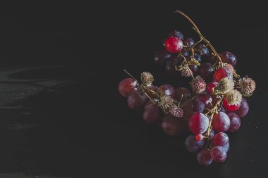 Red grapes, large bunch of fruits, fresh and tasty simple food with bright colors on a black background. flowers and fruit for an artistic food composition.