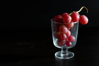 Red grapes, large bunch of fruits, fresh and tasty simple food on a dark background in a fancy minimal composition
