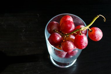 Red grapes, large bunch of fruits, fresh and tasty simple food on a dark background in a fancy minimal composition