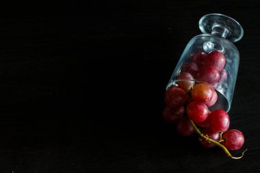 Red grapes, large bunch of fruits, fresh and tasty simple food on a dark background in a fancy minimal composition