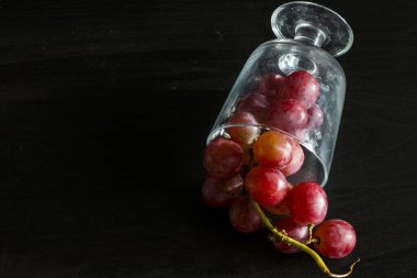 Red grapes, large bunch of fruits, fresh and tasty simple food on a dark background in a fancy minimal composition