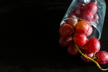 Red grapes, large bunch of fruits, fresh and tasty simple food on a dark background in a fancy minimal composition