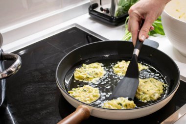 Genç, çekici İsveçli kadın mutfağında yemek pişiriyor ve ailesi için sağlıklı Akdeniz yemekleri hazırlıyor. Genç yemek blogcusu mutfağında yemek hazırlıyor, sebze kızartıyor.