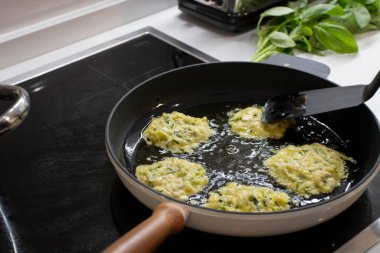Genç, çekici İsveçli kadın mutfağında yemek pişiriyor ve ailesi için sağlıklı Akdeniz yemekleri hazırlıyor. Genç yemek blogcusu mutfağında yemek hazırlıyor, sebze kızartıyor.