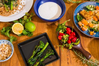 Ahşap bir masada ızgara sebze ve sağlıklı yemek tabakları. Kuşkonmaz, tofu, seitan ve Halloumi peynirli Akdeniz yemekleri. Formda kişiler için glütensiz tarifler. Yiyecek Arkaplanı