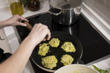 Genç, çekici İsveçli kadın mutfağında yemek pişiriyor ve ailesi için sağlıklı Akdeniz yemekleri hazırlıyor. Genç yemek blogcusu mutfağında yemek hazırlıyor, sebze kızartıyor.