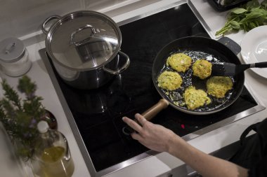 Genç, çekici İsveçli kadın mutfağında yemek pişiriyor ve ailesi için sağlıklı Akdeniz yemekleri hazırlıyor. Genç yemek blogcusu mutfağında yemek hazırlıyor, sebze kızartıyor.