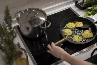 Genç, çekici İsveçli kadın mutfağında yemek pişiriyor ve ailesi için sağlıklı Akdeniz yemekleri hazırlıyor. Genç yemek blogcusu mutfağında yemek hazırlıyor, sebze kızartıyor.