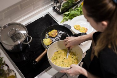Genç, çekici İsveçli kadın mutfağında yemek pişiriyor ve ailesi için sağlıklı Akdeniz yemekleri hazırlıyor. Genç yemek blogcusu mutfağında yemek hazırlıyor, sebze kızartıyor.