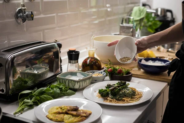 Young charming Swedish woman cooking at home in her kitchen, preparing healthy mediterranean food for her family. Young food blogger doing food preparation in her kitchen, frying vegetables