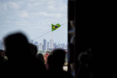 Brezilya 'da bir evde mavi bulutlu bir gökyüzünde bayrak direğinde dalgalanan Brezilya bayrağı. Etrafta gölgeler var. Kraliyet mensubu olmayan fotoğraf numarası: 1360603520Brezilya bayrağı. Brezilya Federasyon Cumhuriyeti 'nin güzel bayrağı.