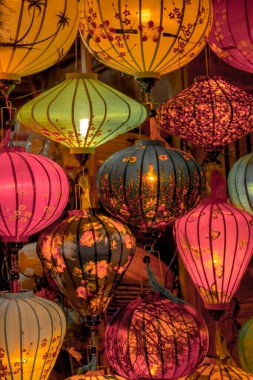 Hoi An, Vietnam - 09-04-2018: Colorful view of busy street and crowded river in Hoi An, Vietnam, famous for mixed cultures and architecture. Traditional colorful lanterns spread light all around. clipart