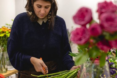 Çiçekçi olarak küçük bir dükkanda çalışan genç bir kadını ve çiçek filizlerini kırbaçlayan iş kadını konseptini görmek..