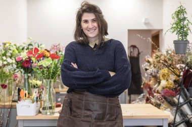 Çiçekçi olarak çalışan neşeli genç bir kadının portresi. Önlük takıyor, genç bir iş kadını..