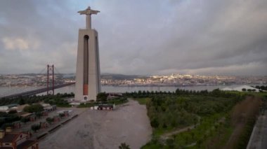 Aerial drone view flyby past Sanctuary of Christ the King Portuguese Santuario de Cristo Rei is Catholic monument next to the 25 de April bridge overlooking city of Lisbon Almada