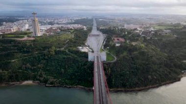 Aerial drone view flyby past Sanctuary of Christ the King Portuguese Santuario de Cristo Rei is Catholic monument next to the 25 de April bridge overlooking city of Lisbon Almada
