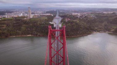 Aerial drone view flyby past Sanctuary of Christ the King Portuguese Santuario de Cristo Rei is Catholic monument next to the 25 de April bridge overlooking city of Lisbon Almada