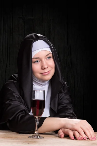 Nunna vid bordet med glas vin — Stockfoto