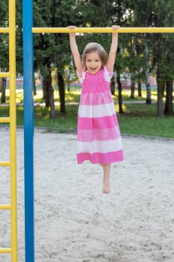 Yatay bir çubuk üzerinde asılı kız