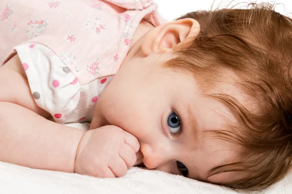 Bonito bebê chupa seu polegar deitado na cama — Fotografia de Stock