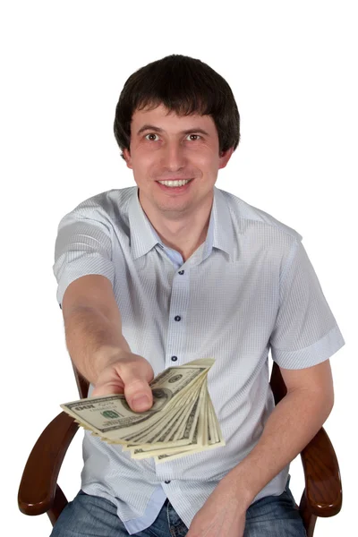 Businessman sitting on a chair holds out dollars — Stock Photo, Image