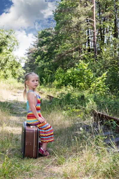 Linda niña sentada en una maleta grande —  Fotos de Stock