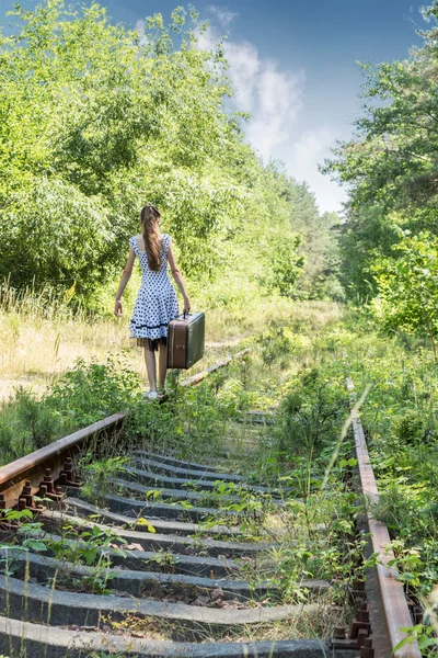 Dívka s kufrem, chůzi po kolejích — Stock fotografie