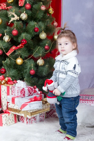 Girl with toy at Christmas tree — Stock Photo, Image