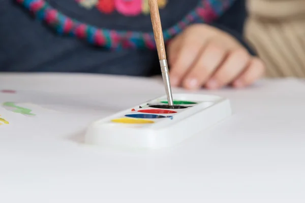 Criança mão mergulha o pincel em aquarela — Fotografia de Stock