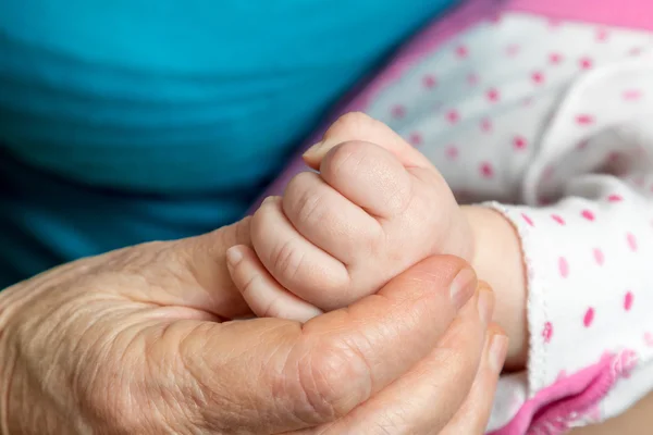 Velha mão mulher segurando palma bebê — Fotografia de Stock
