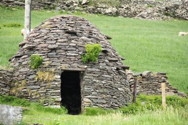 Early medieval stone-built round house clochain (beehive hut) on Dingle Peninsula, Kerry, Ireland. A Clochain is a dry-stone hut with a corbelled roof, commonly associated with the south-western Irish Fahan Group from 2000 bc clipart