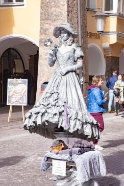 Eski Innsbruck kasabasının merkez caddesinde yaşayan bir heykel kılığına girmiş gümüş metalik bir elbise giymiş bir sokak sanatçısı. 15 Ekim 2016 'da Avusturya' nın Innsbruck kentinde çekildi.