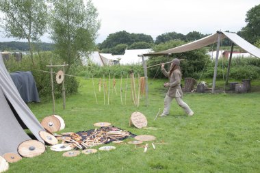 Viking Haithabu köyünde orta yaşlı Viking kıyafetleri giymiş bir aktör geleneksel Viking silahlarıyla başa çıkma yeteneğini sergiliyor. 15 Temmuz 2016 'da Busdorf, Almanya' da çekildi.