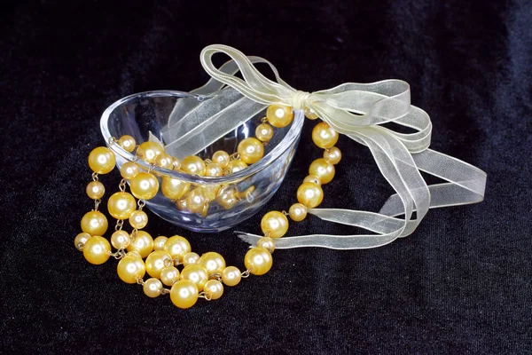 Golden pearls in love shape glass — Stock Photo, Image