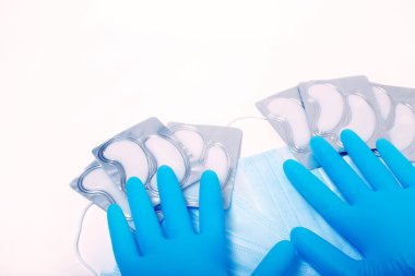 Beauty accessories on white background. Blue gloves, masks, and patches.