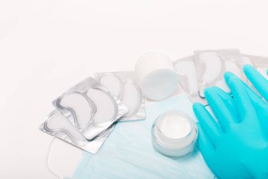 Beauty accessories on white background. Blue gloves, masks, cream and patches.