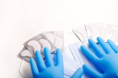 Beauty accessories on white background. Blue gloves, masks, and patches.