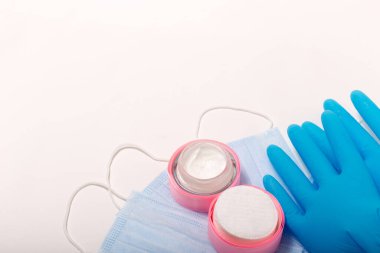 Beauty accessories on white background. Blue gloves, masks, and cream.