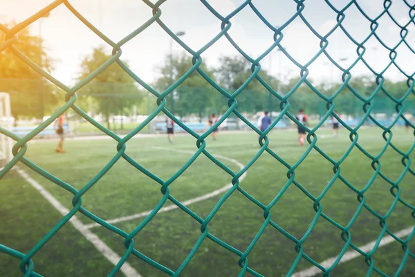 Maschendrahtzaun vom Fußballplatz mit wettbewerbsfähigem. — Stockfoto