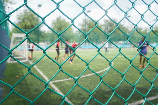 Maschendrahtzaun vom Fußballplatz mit Wettbewerb im öffentlichen Raum. — Stockfoto