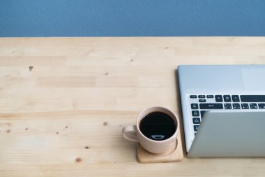 Dizüstü bilgisayar ve sade kahve içeren ofis masası.