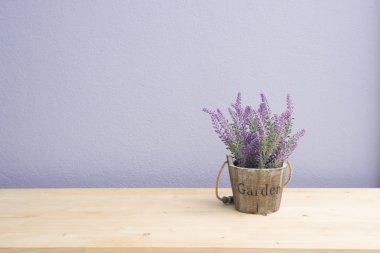Mor lavanta çiçekli ahşap masa çiçek saksısı ve mor çimento duvar.