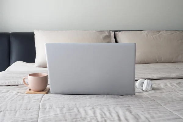 Ліжко з ранковою кавою, навушники і ноутбук. — стокове фото