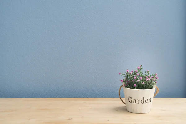 Tavolo in legno rosa su vaso di fiori e muro di cemento blu . — Foto Stock