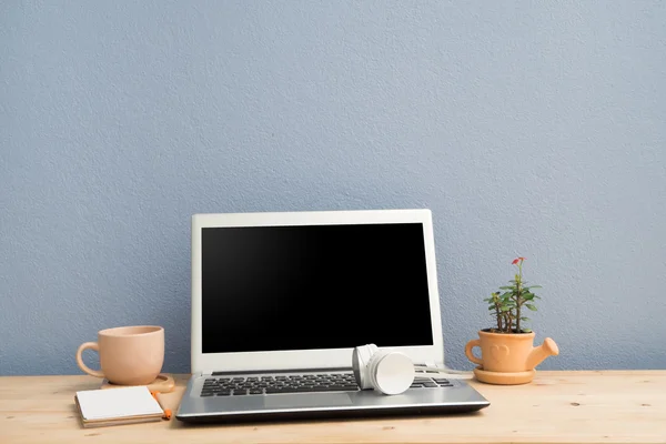 Skrivbord med bärbar dator, anteckningspapper, kaffekopp och Euphorbia milii blomma på terrakotta blomma Pot. — Stockfoto