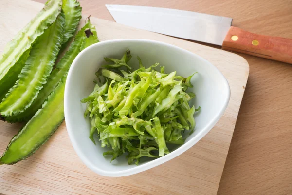 Sliced winged bean vegetable on the white dish and wooden block. — Stock Photo, Image